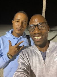 two men posing for a selfie on the beach